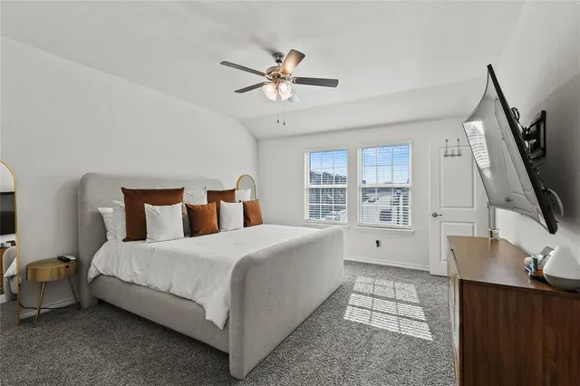 a spacious bedroom with a bed a flat screen tv and a large window with the outer view