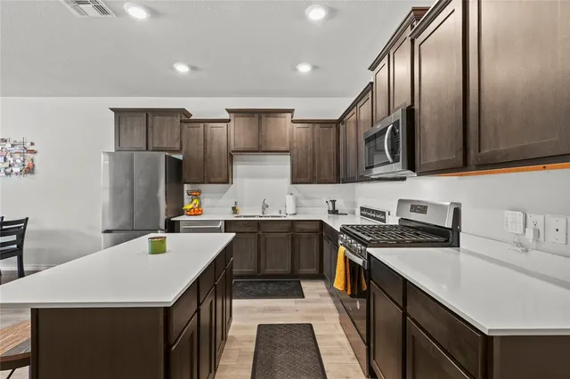 a kitchen with stainless steel appliances granite countertop a sink stove refrigerator and cabinets