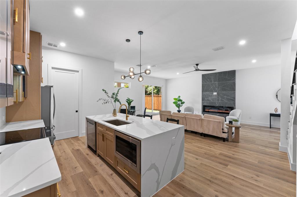 2826 Rochester Street Dallas, TX 75215 - Photo 12 of 38 Kitchen with decorative light fixtures, brown cabinetry, light wood finished floors, light stone countertops, and recessed lighting