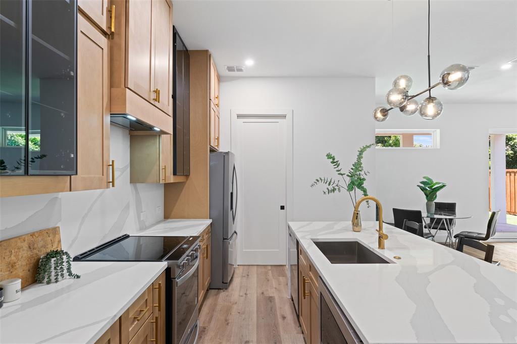 2826 Rochester Street Dallas, TX 75215 - Photo 13 of 38 Kitchen with light stone counters, pendant lighting, stainless steel appliances, light wood-style flooring, and brown cabinets
