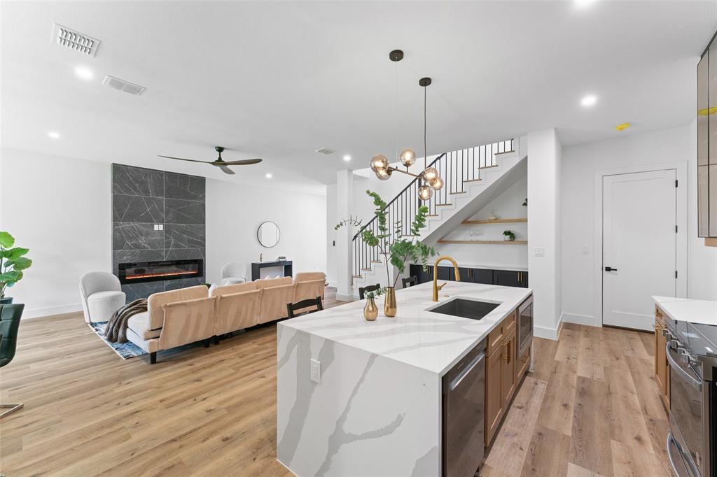 2826 Rochester Street Dallas, TX 75215 - Photo 14 of 38 Kitchen featuring hanging light fixtures, an island with sink, light stone counters, a premium fireplace, and appliances with stainless steel finishes