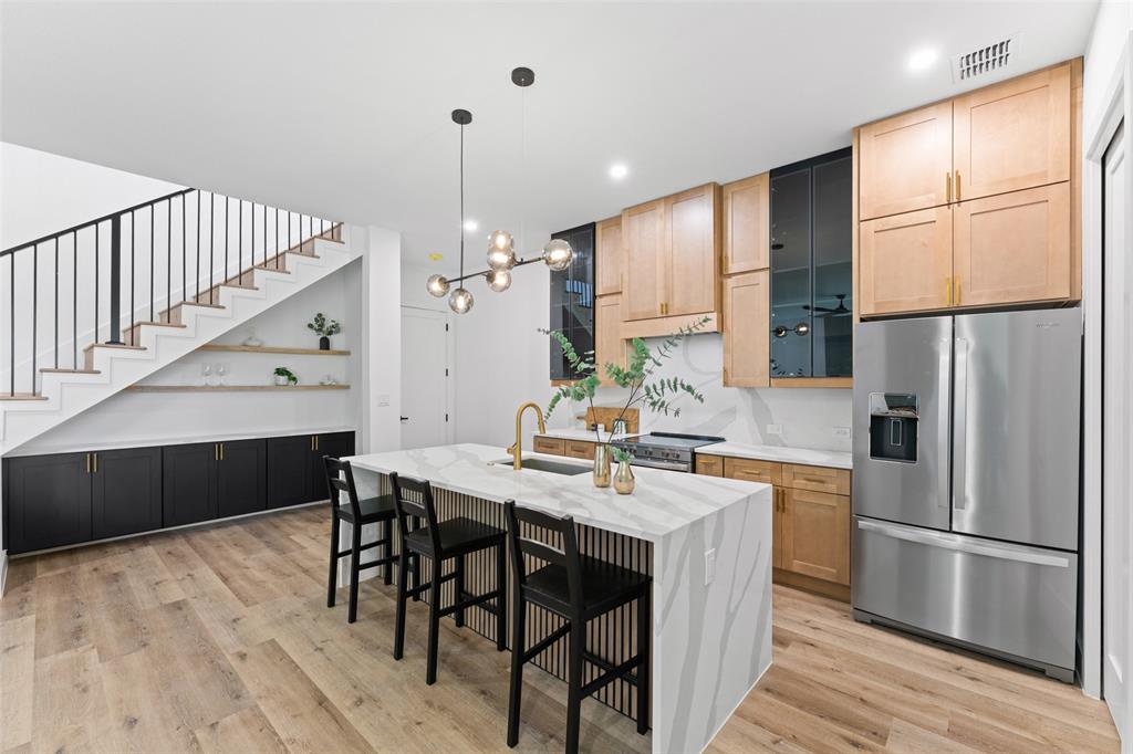 2826 Rochester Street Dallas, TX 75215 - Photo 15 of 38 Kitchen with appliances with stainless steel finishes, a center island with sink, a kitchen breakfast bar, light stone countertops, and pendant lighting