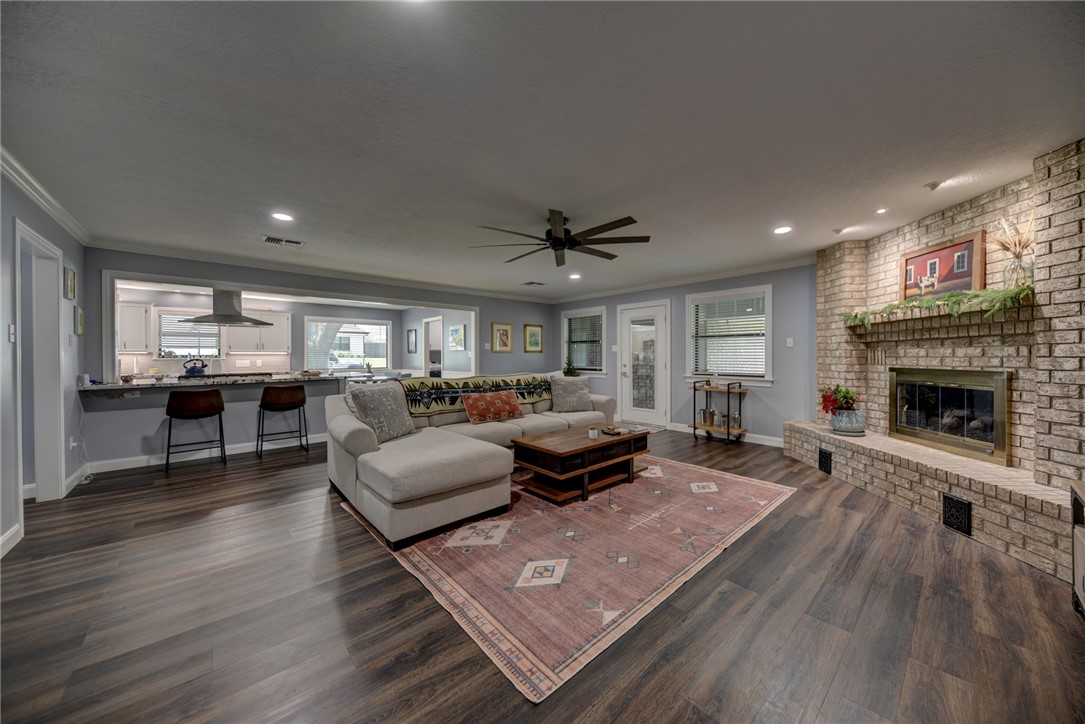 1600 Pecan Street Brenham, TX 77833 - Photo 7 of 33 Living area featuring crown molding, ceiling fan, a fireplace, baseboards and dark wood-style flooring