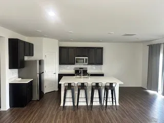 a kitchen with stainless steel appliances a table chairs refrigerator and microwave