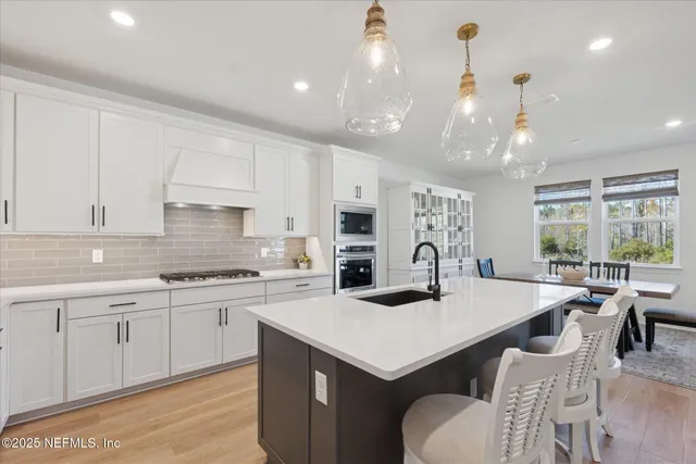 a kitchen with a sink dishwasher stove and white cabinets with wooden floor