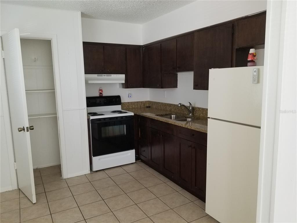 1306 East 137th Avenue, Unit B Tampa, FL 33613 - Photo 3 of 10 a kitchen with a refrigerator sink and cabinets
