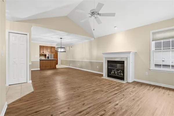 a view of a livingroom with a fireplace a ceiling fan and wooden floor
