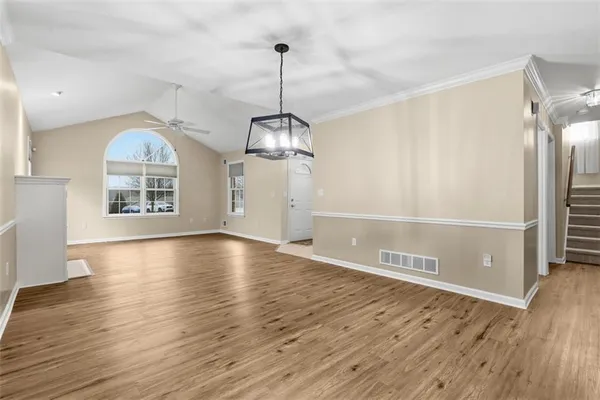 a view of an empty room with window and wooden floor