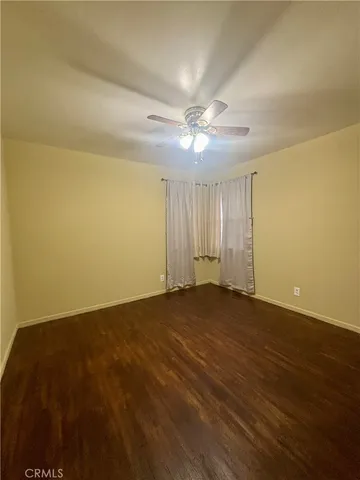 an empty room with a ceiling fan and wooden floor