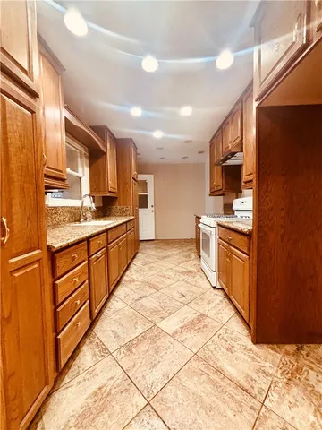 a large kitchen with stainless steel appliances kitchen island granite countertop a refrigerator and cabinets