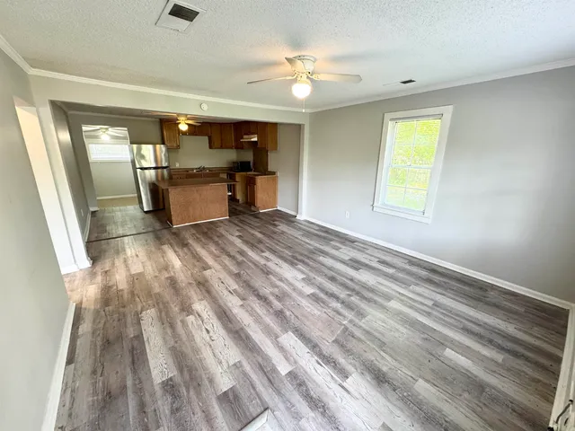 a view of an empty room with window and a kitchen