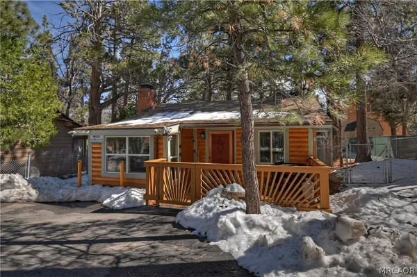 a view of a house with a wooden deck and a large tree
