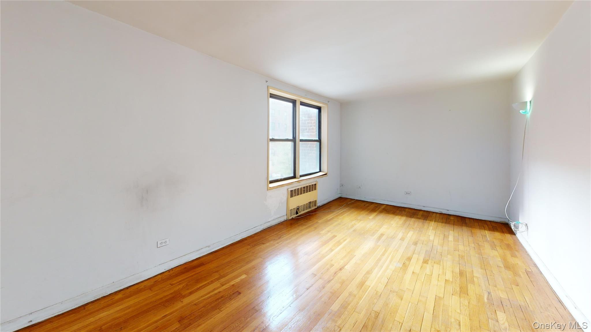 33-26 92nd Street, Unit 2T Queens, NY 11372 - Photo 6 of 10 an empty room with wooden floor and windows
