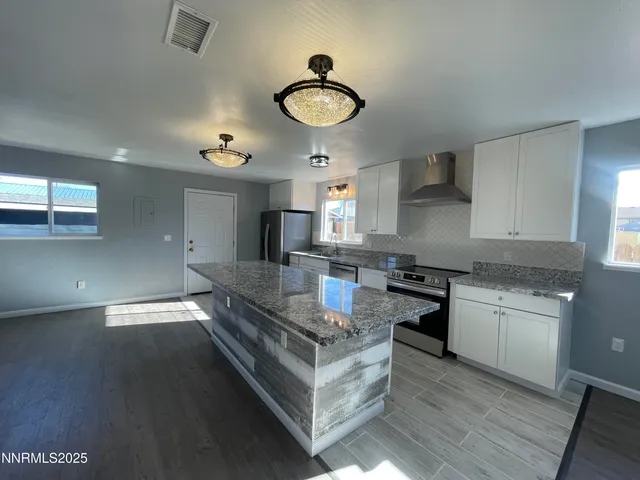 a kitchen with granite countertop a stove a sink and a refrigerator