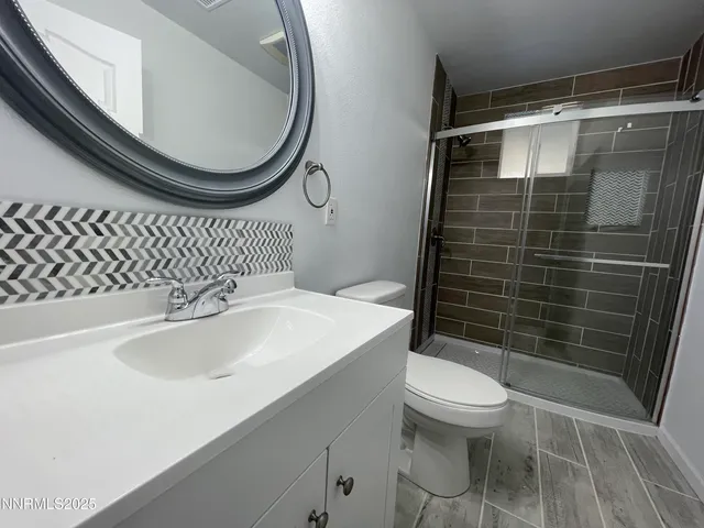 a bathroom with a sink a toilet a mirror and shower