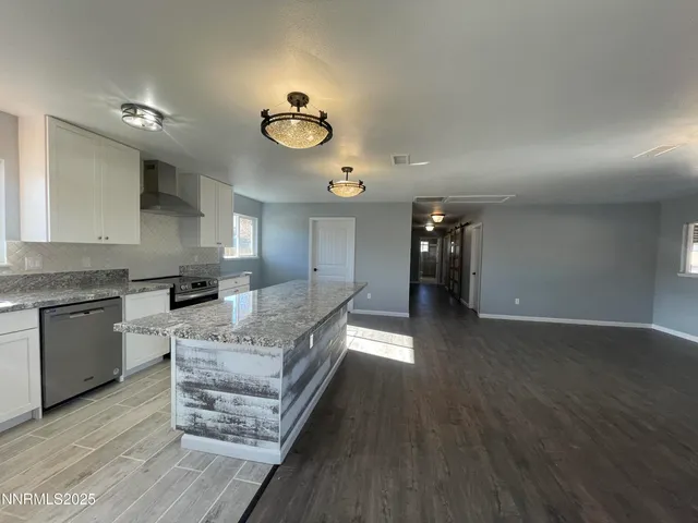 a large kitchen with a wooden floor and stainless steel appliances