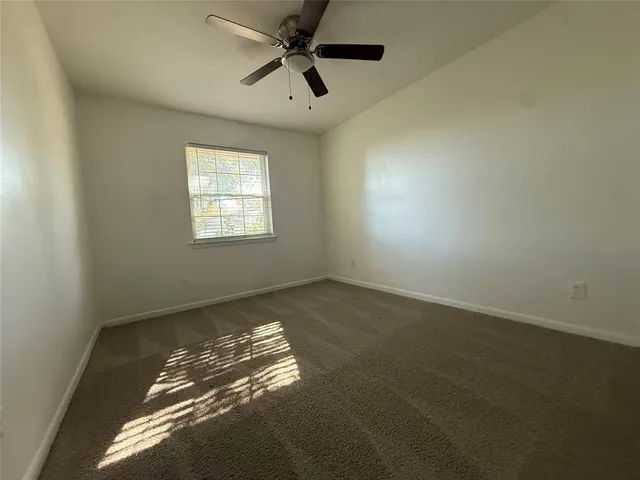 en empty room with windows and ceiling fan