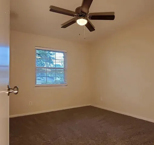 an empty room with a window and a fan