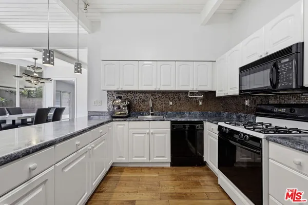 a kitchen with a sink dishwasher and white cabinets with wooden floor