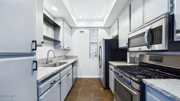 a kitchen with stainless steel appliances granite countertop a sink stove and refrigerator