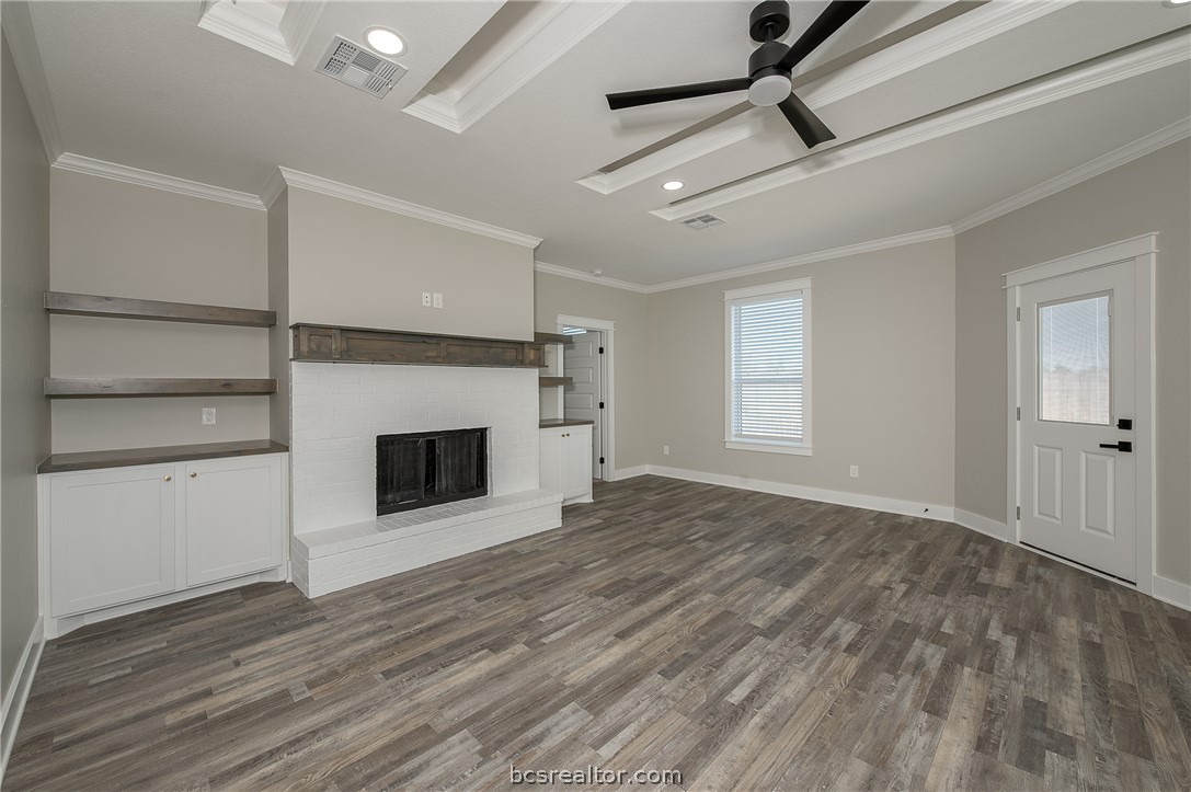2908 GOLDBERG Drive Bryan, TX 77808 - Photo 27 of 44 View of the family room into the kitchen, decorative cove lighting, ceiling fan with lite kit, can lights, gas fireplace, and wood mantle, floating shelves, window treatments, pop up ceilings and vinyl flooring.