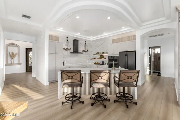 a kitchen with stainless steel appliances kitchen island granite countertop a refrigerator oven a sink dishwasher and white cabinets with wooden floor