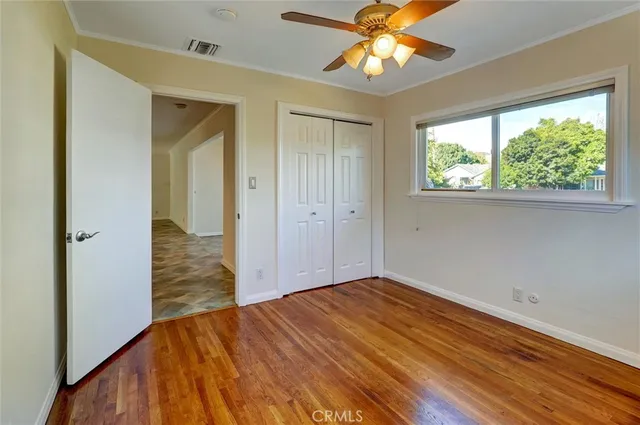 an empty room with wooden floor chandelier fan and closet area