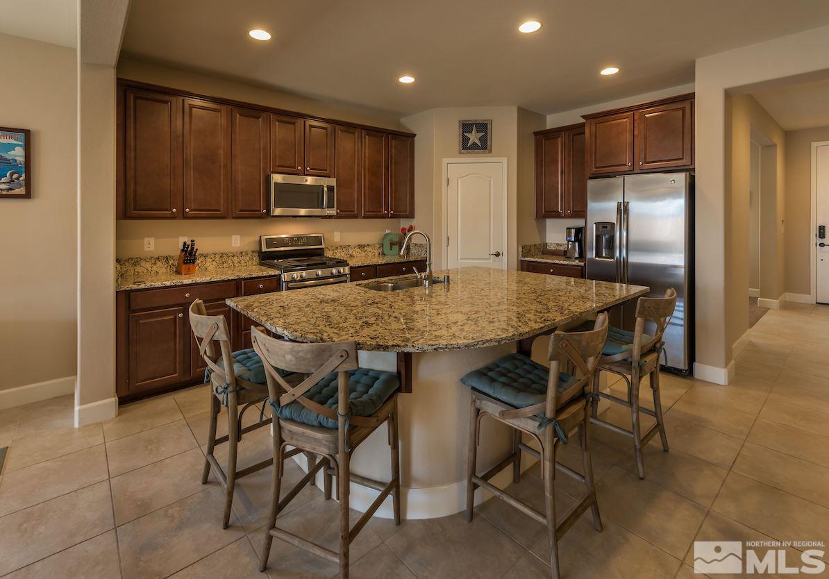 10045 Ignacio Circle Reno, NV 89521 - Photo 4 of 12 a kitchen with granite countertop a table chairs microwave and refrigerator