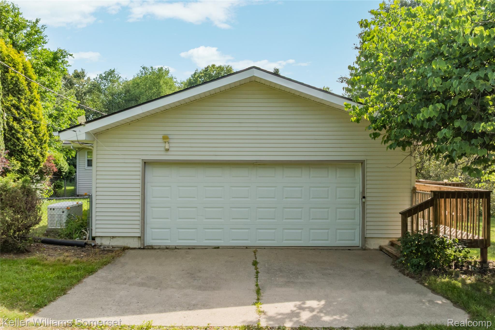 2344 Rochester Road Leonard, MI 48367 - Photo 55 of 66 Attached garage featuring a panel-style door, light-colored siding, and a concrete driveway