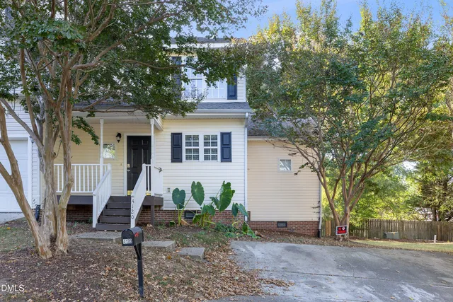 a view of a house with a tree and wooden fence