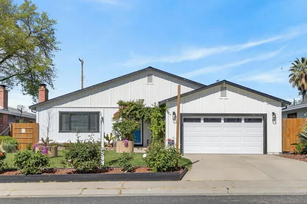 a front view of a house with garage and plants