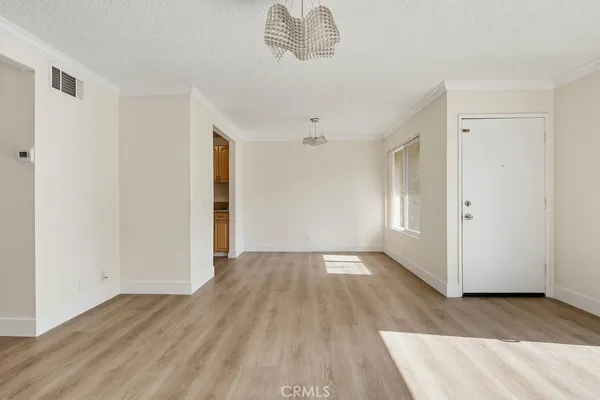 an empty room with wooden floor cabinet and windows