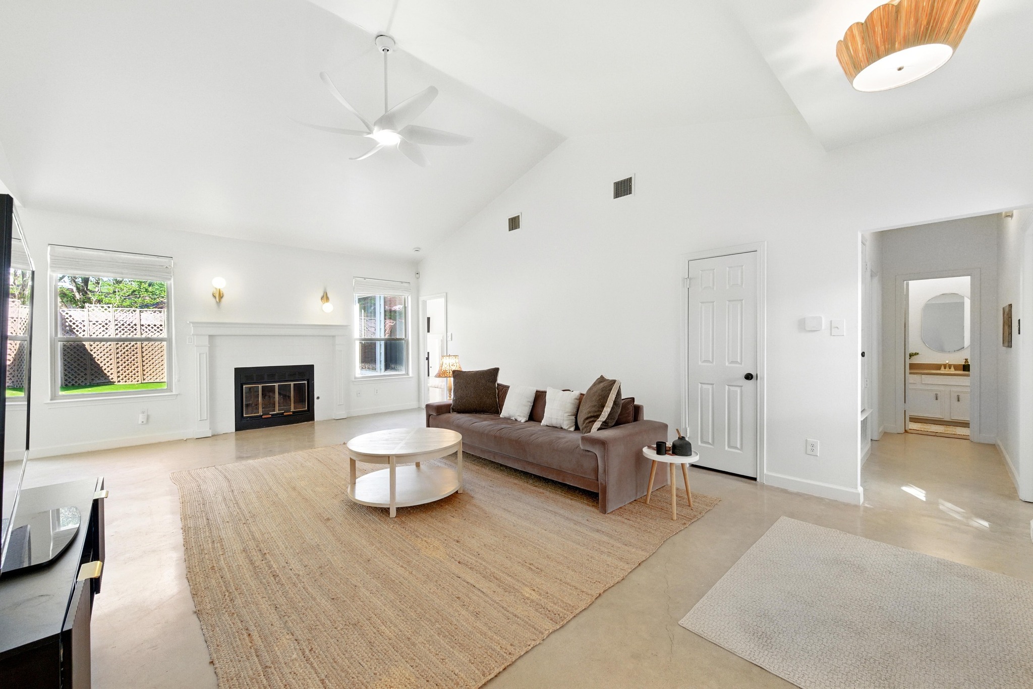5807 Convict Hill Road Austin, TX 78749 - Photo 4 of 27 Soaring ceilings and abundant natural light define this spacious living room. The clean lines of the fireplace, flanked by tall windows, create a cozy yet airy focal point. Sleek concrete floors enhance the home's modern appeal while offering easy maintenance.