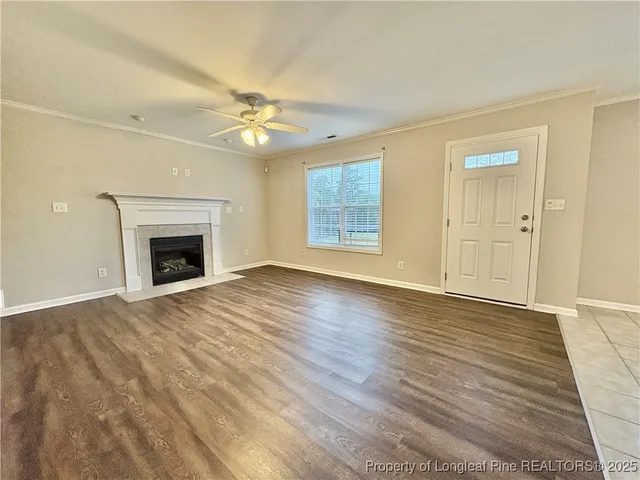 an empty room with wooden floor fireplace and fan