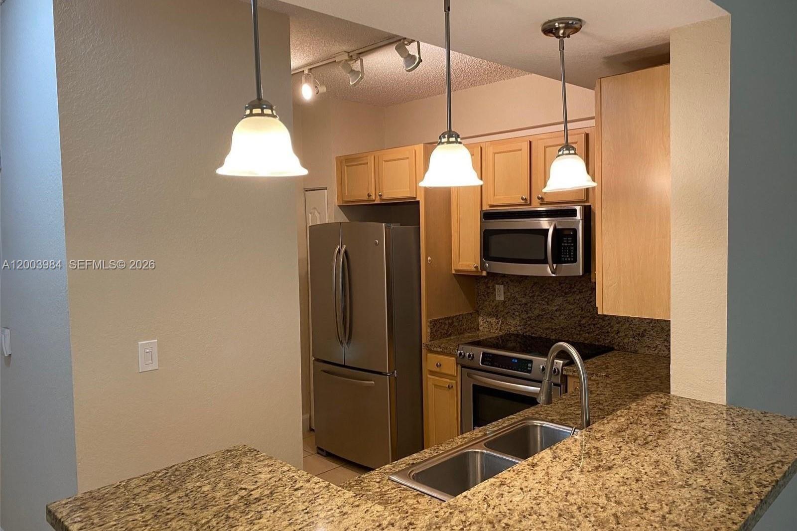 6001 Southwest 70th Street, Unit 342 South Miami, FL 33143 - Photo 4 of 19 a kitchen with stainless steel appliances granite countertop a refrigerator a oven a sink and a table
