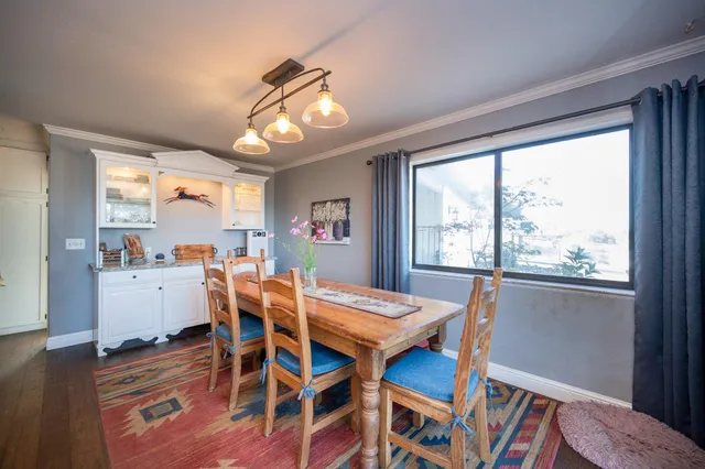 a open kitchen with stainless steel appliances granite countertop a stove a refrigerator and a dining table with wooden floor