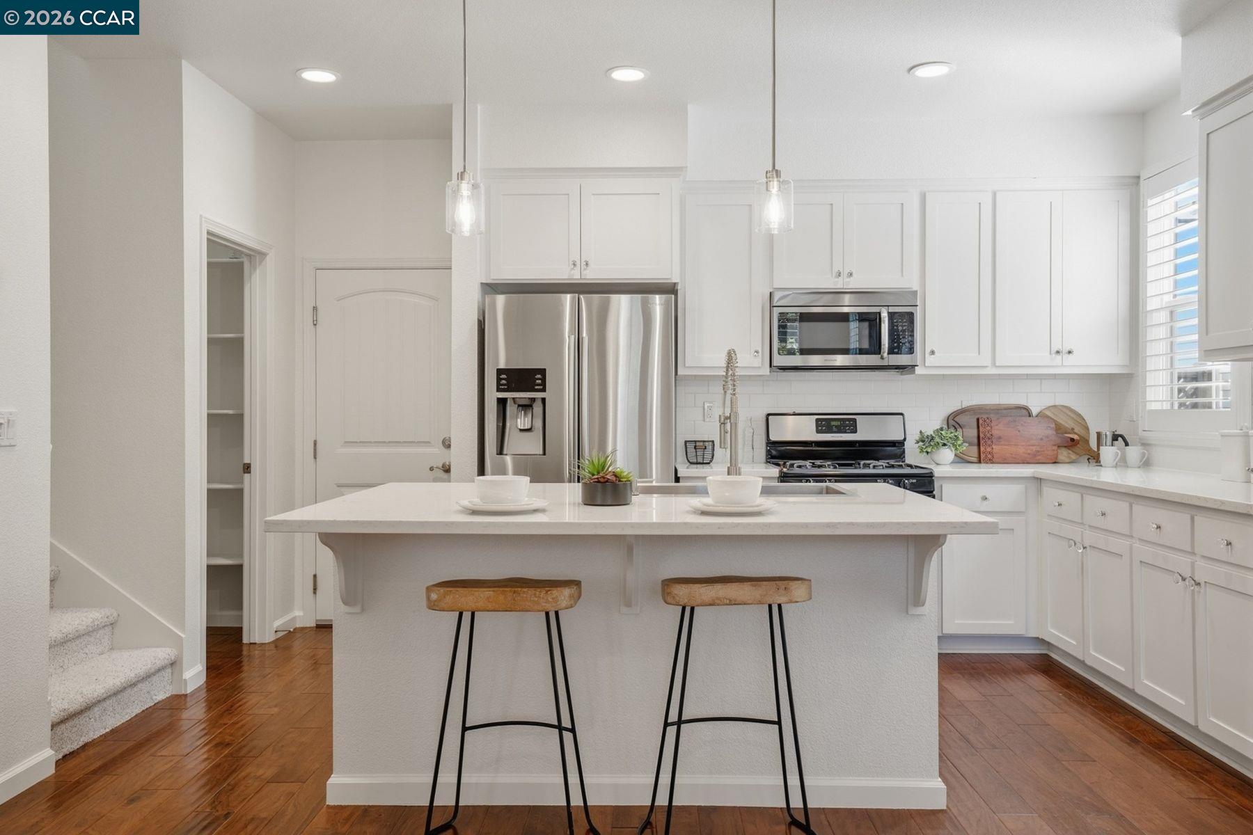 22640 Filbert Street Hayward, CA 94541 - Photo 15 of 60 a kitchen with stainless steel appliances kitchen island granite countertop a sink a stove a refrigerator and white cabinets with wooden floor
