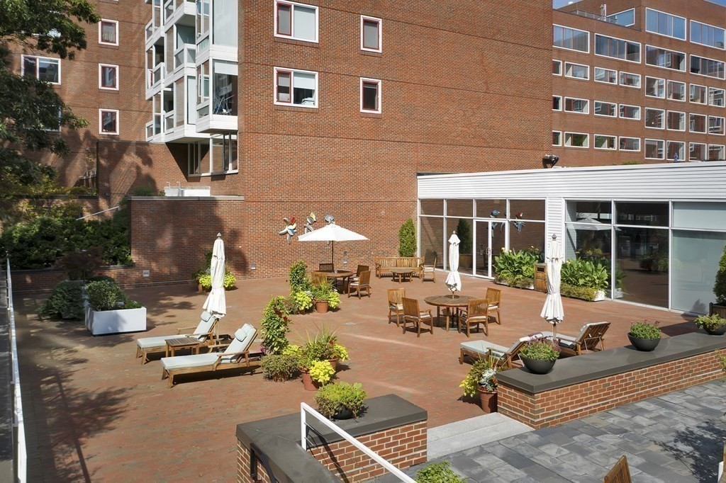 975 Memorial Drive, Unit 906 Cambridge, MA 02138 - Photo 28 of 37 a front view of a building with outdoor seating and a tree