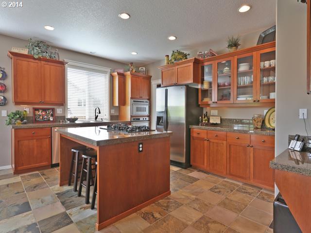 4920 Northwest 146th Place Portland, OR 97229 - Photo 4 of 16 a kitchen with stainless steel appliances granite countertop a refrigerator a sink a stove a dining table and chairs