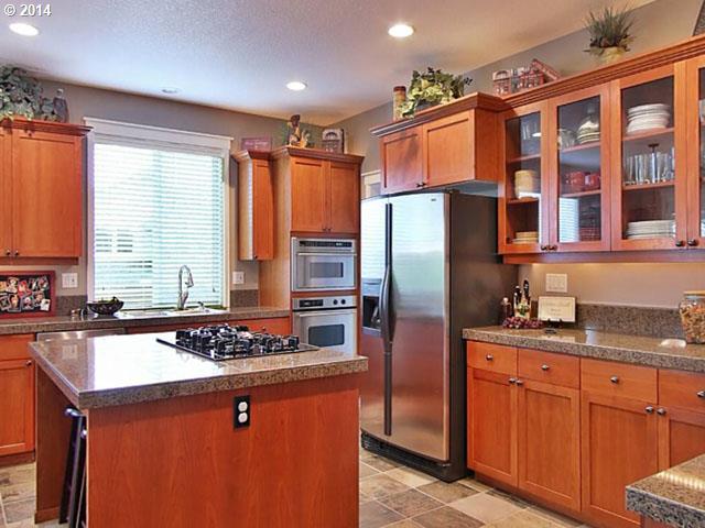 4920 Northwest 146th Place Portland, OR 97229 - Photo 5 of 16 a kitchen with stainless steel appliances granite countertop a refrigerator a sink dishwasher a stove a dining table and chairs with wooden floor
