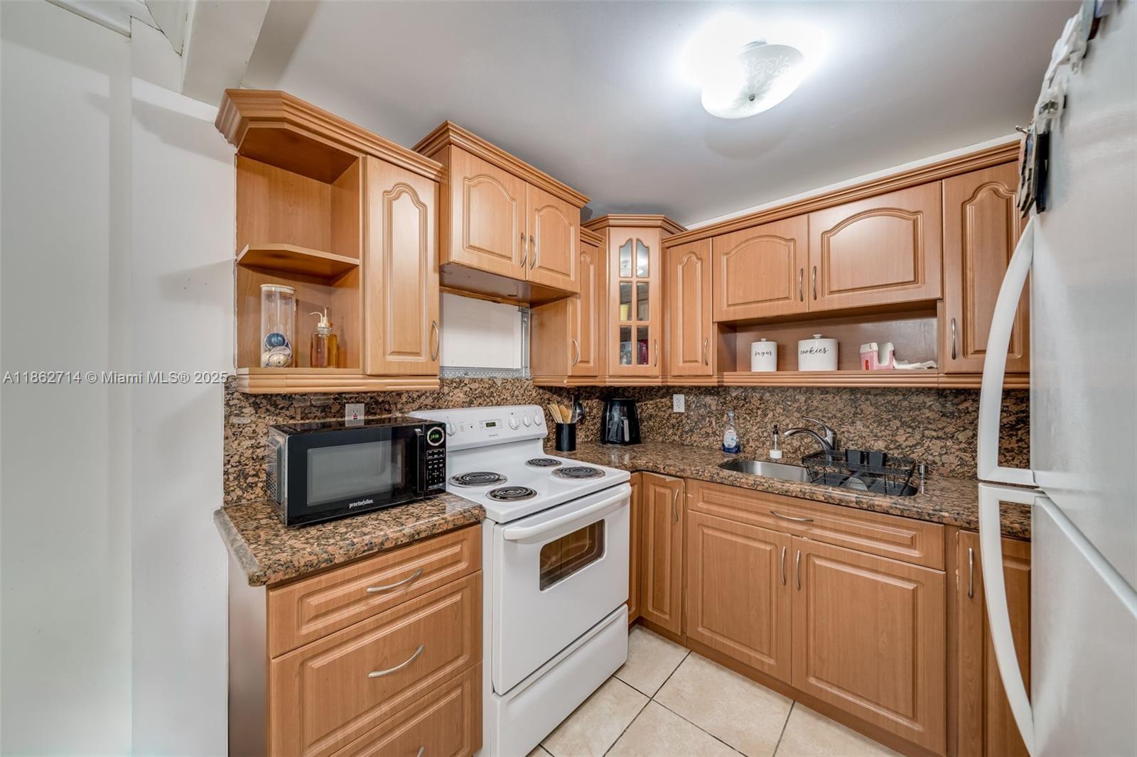 1221 Southwest 122nd Avenue, Unit 215 Miami, FL 33184 - Photo 19 of 57 a kitchen with stainless steel appliances granite countertop a stove and a refrigerator