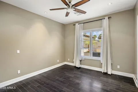 an empty room with wooden floor and a ceiling fan