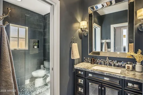 a bathroom with a granite countertop sink a toilet a mirror and shower