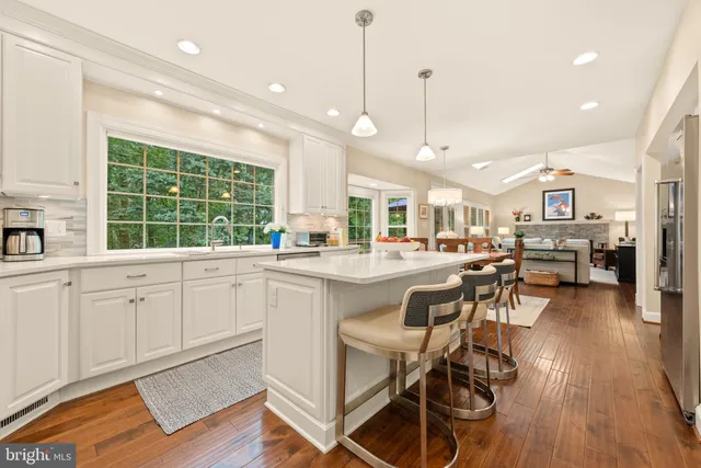 a kitchen with stainless steel appliances granite countertop a stove a sink a oven a dining table and chairs with wooden floor