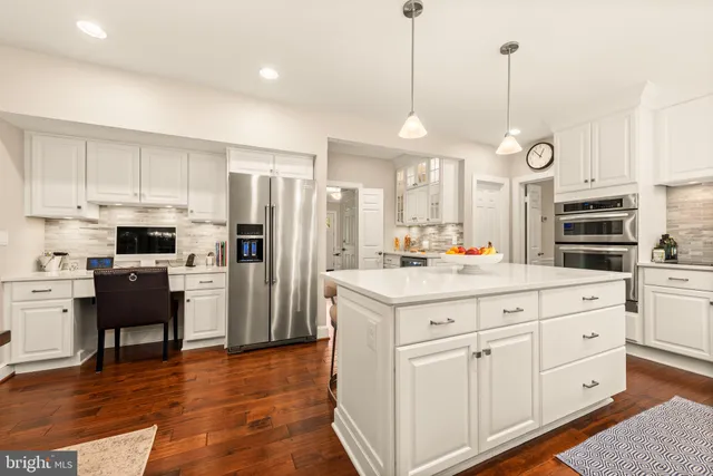 a kitchen with stainless steel appliances granite countertop a stove a sink dishwasher a refrigerator white cabinets and wooden floor