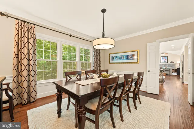 a view of a dining room and a livingroom with furniture wooden floor a chandelier