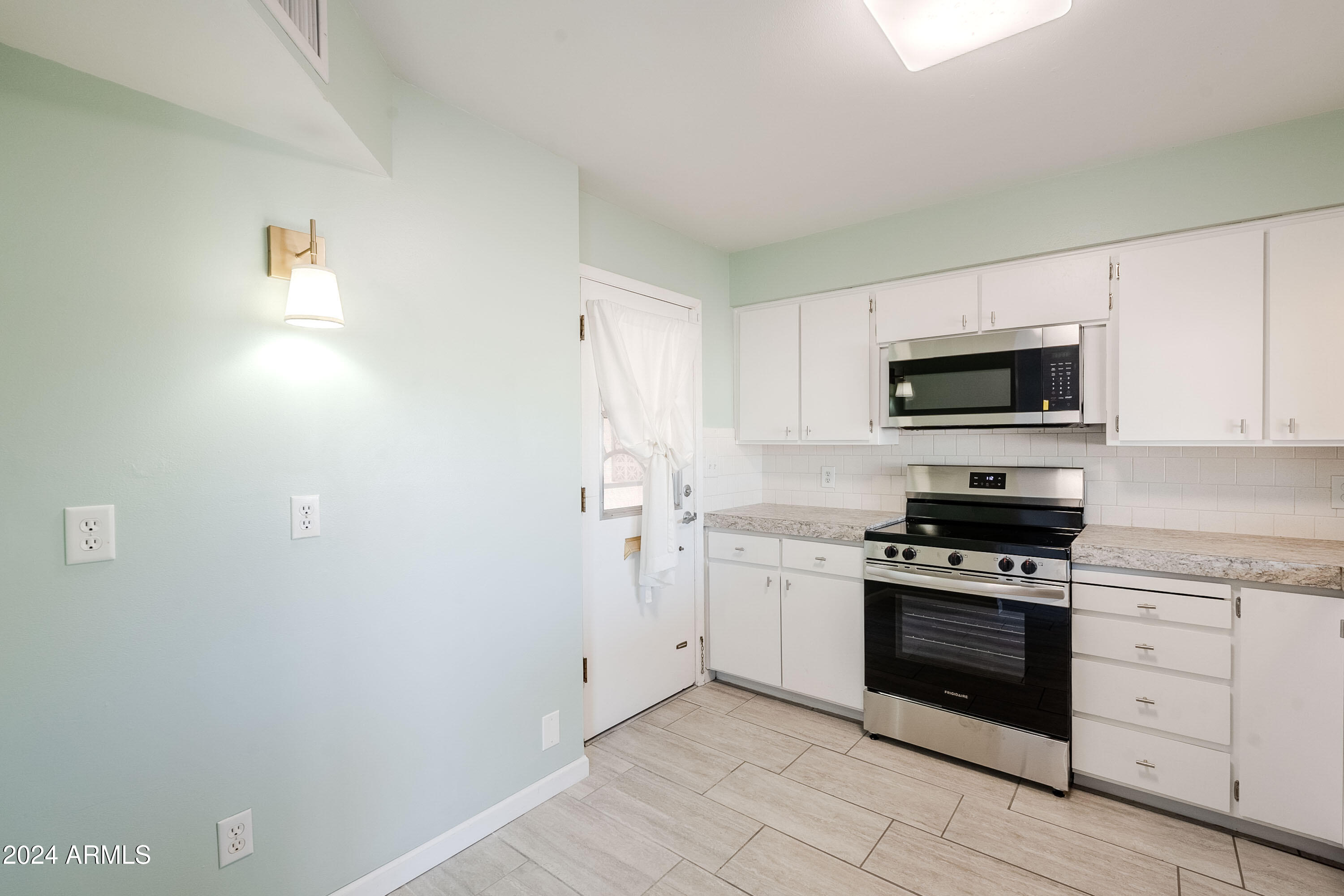 5914 East Decatur Street Mesa, AZ 85205 - Photo 4 of 37 a kitchen with white cabinets and stainless steel appliances