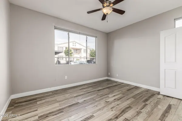 a view of an empty room with wooden floor and a window