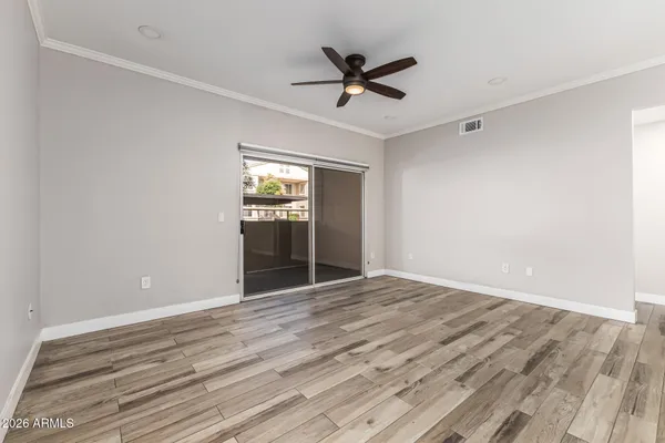 a view of empty room with wooden floor and ceiling fan
