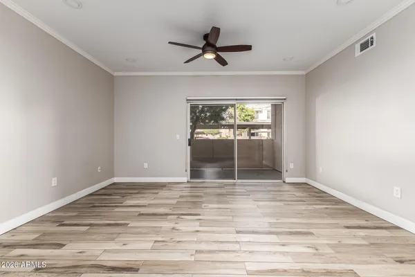 a view of empty room with wooden floor and fan